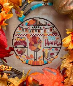 a cross stitch thanksgiving sampler surrounded by autumn leaves