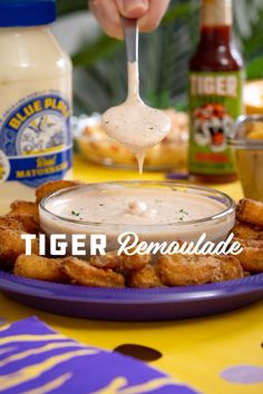 a person dipping some kind of sauce on chicken wings with ranch dressing in the background