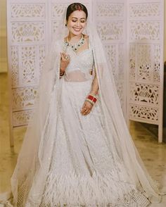 a woman in a white wedding dress and veil posing for the camera with her hand on her hip