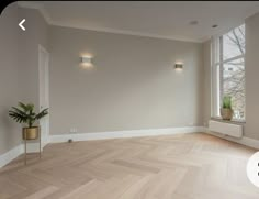 an empty room with wood flooring and two planters on the windowsills