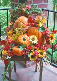 pumpkins and flowers are arranged on a chair