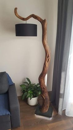 a living room with a couch, chair and wooden tree trunk lamp on the floor