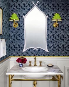 a white sink sitting under a mirror next to a wall mounted faucet in a bathroom