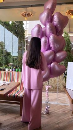 a woman standing in front of a large bunch of balloons on the floor with her back to the camera