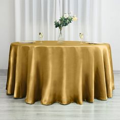 the table is covered with a gold cloth and two glasses are on top of it