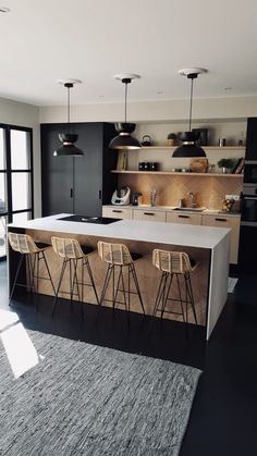 a kitchen with an island and bar stools in the center, along with black cabinets