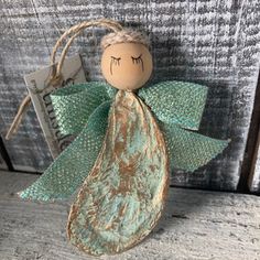 an angel ornament hanging from a string on a wooden surface with a tag