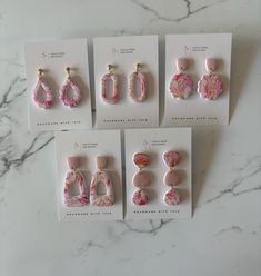 four pairs of pink and white earrings on top of a card next to each other