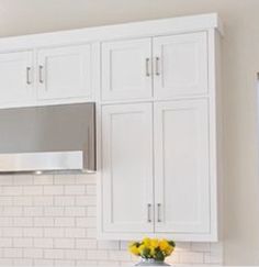 a kitchen with white cabinets and stainless steel range hood over the stove, microwave and dishwasher