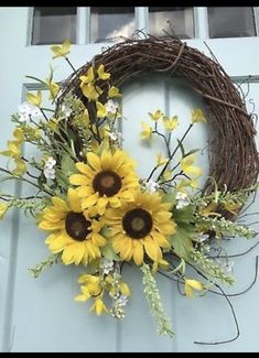 a wreath with sunflowers and greenery hanging on a door