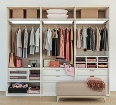 an organized closet with clothes hanging on the shelves and drawers next to a footstool