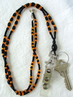 Orange & Black Beaded Lanyard This Orange & Black Beaded Lanyard can be used as a badge holder, an I.D. holder, keychain necklace, watch holder - it's a multi-use accessory for home or office! 34" in length, long enough to put on or remove overhead. It also has an easy-to-use metal lobster clasp for your convenience. It's made with orange and black glass beads and strung on strong C-Lon beading cord. Snap-on badge holder, clip, and keyring are included to keep your badges or keys ready when you Everyday Black Beaded Jewelry, Adjustable Black Lanyard With Key Clip, Adjustable Black Lanyards With Key Clip, Black Beaded Adjustable Lanyards, Adjustable Black Badge Holder With Key Leash, Black Lanyard With Lobster Clasp As Gift, Black Beaded Lanyard As Gift, Black Beaded Lanyards As Gift, Black Beaded Lanyards For Gift