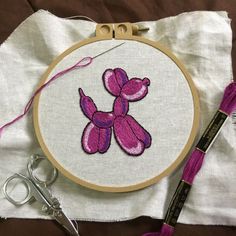 a pink teddy bear is in the middle of a embroidery project with scissors and thread