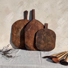 three wooden cutting boards sitting next to each other on top of a white table cloth