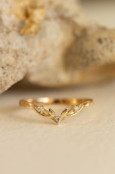 a gold ring with three small diamonds on it sitting next to a rock and stone