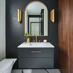 a white toilet sitting next to a bathroom sink under a large mirror on a wall