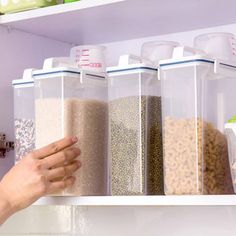 a person's hand reaching for some food in their pantry bins on the shelf