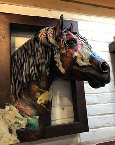 a horse head mounted to the side of a brick wall next to a window with paint splattered on it