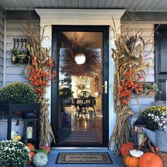 a front porch decorated for fall with pumpkins and corn stalks