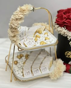 two tiered trays filled with white and gold cookies on top of a table