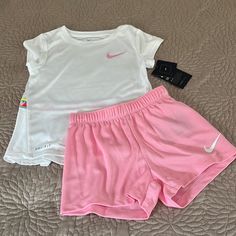 two baby girls'nike shorts and t - shirt on a bed