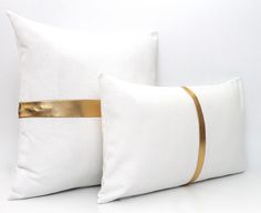 two white pillows with gold ribbon on them