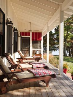 two lawn chairs sitting on the front porch of a house with red and white striped curtains