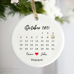 a personalized ornament hanging from a christmas tree with flowers in the background