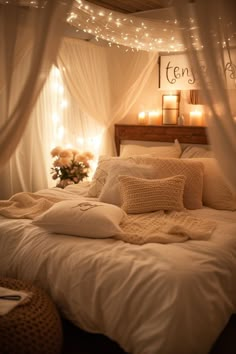 a bed with white linens and lights on the headboard is lit by candles