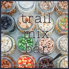 a table topped with jars filled with different types of food and the words trail mix bar