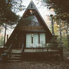 a house in the woods with stairs leading up to it's front door and porch