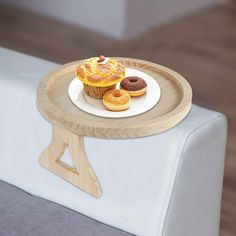 two donuts on a wooden tray sitting on top of a white chair next to a cupcake