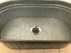 a stainless steel sink in a bathroom with wood flooring