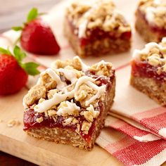 strawberry crumbler bars on a cutting board with strawberries in the foreground