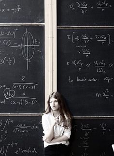 a woman standing in front of a blackboard with many calculations on it