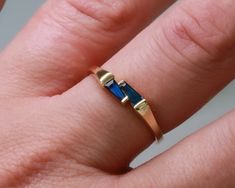 a woman's hand with a gold and blue ring on top of her finger