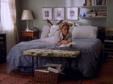 a woman laying on top of a bed next to a table with an open book