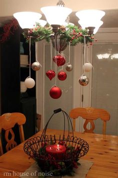 christmas decorations hanging from a chandelier over a dining room table with red and white baubles