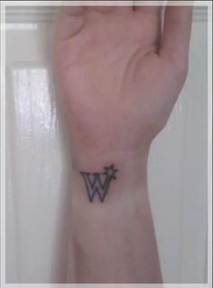 a person's wrist tattoo with the letter w on it, in black ink