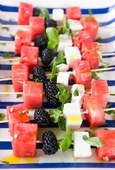 watermelon and blackberries skewers with mint leaves on a blue and white striped plate