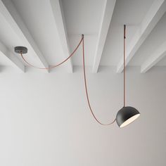 two lamps hanging from the ceiling in an empty room with white walls and beams on either side