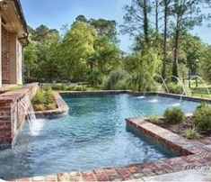 an outdoor swimming pool surrounded by brick walls and water features with a waterfall running down the side