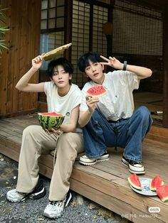 two young men sitting on steps holding watermelon slices