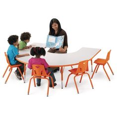 a group of children sitting at a table with an adult and two children reading books