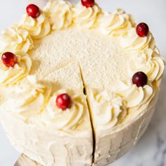 a cake with white frosting and cranberries on top is being cut by a knife