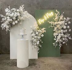 two white vases with flowers on them next to a neon sign