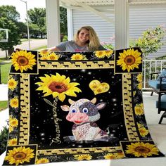 a woman holding up a blanket with a cow and sunflowers on it