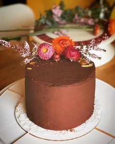 there is a chocolate cake with flowers on the top and bottom, sitting on a white plate