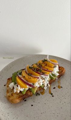 a white plate topped with toast covered in fruit and cheese on top of it's side