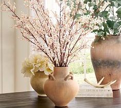 two vases with flowers in them sitting on a table